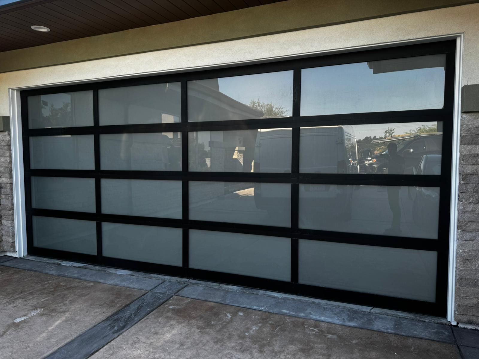 Black aluminum full-view garage door with frosted glass panels.