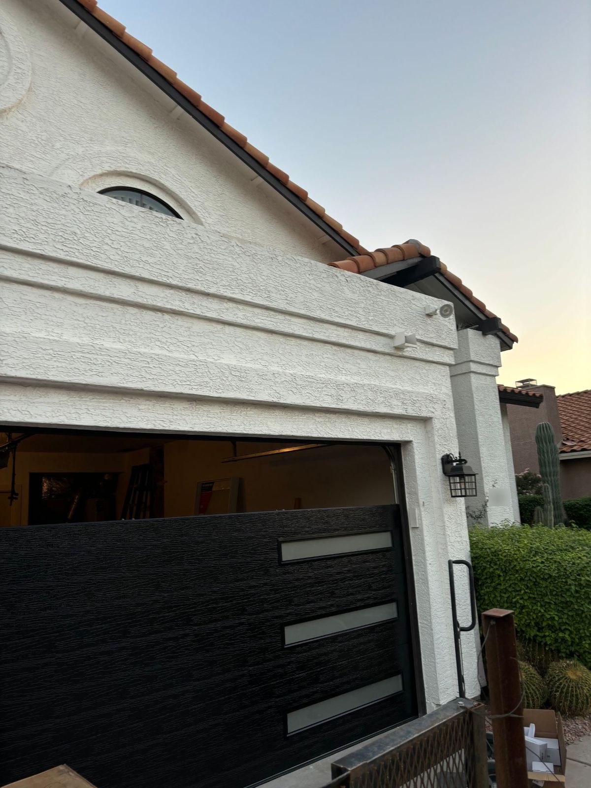 Black wood-grain garage door with frosted window inserts being installed.