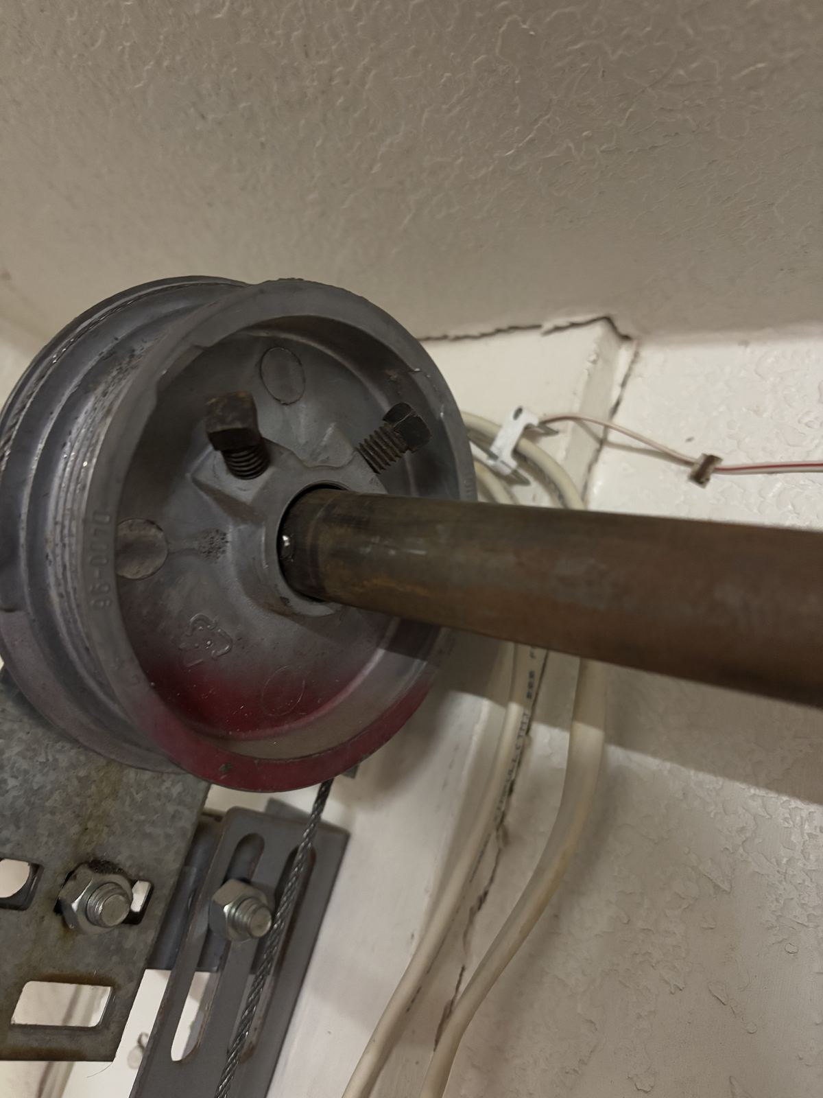 Close-up of a garage door cable drum on the torsion shaft.