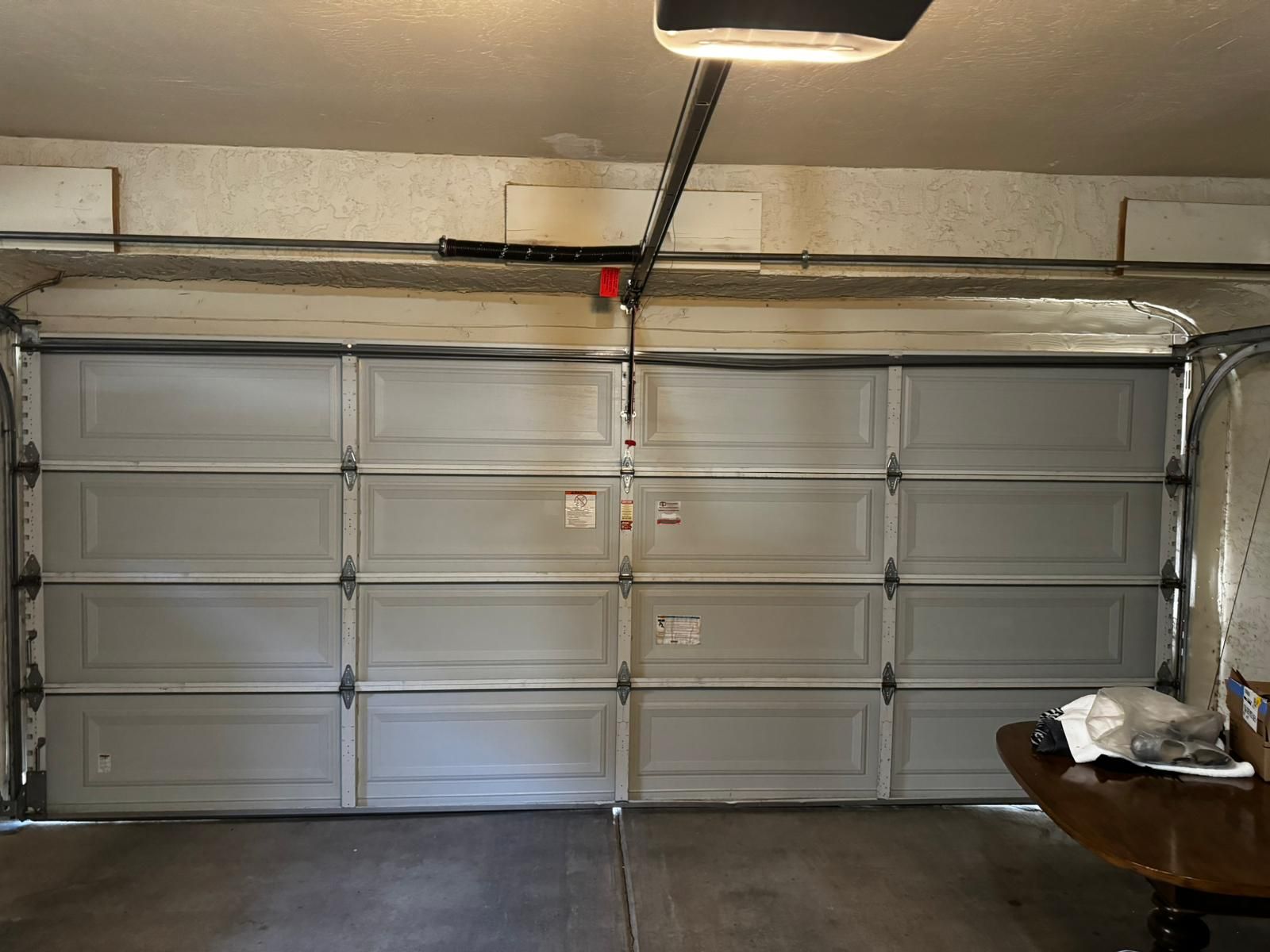 Raised-panel garage door with torsion spring and opener rail, inside view.